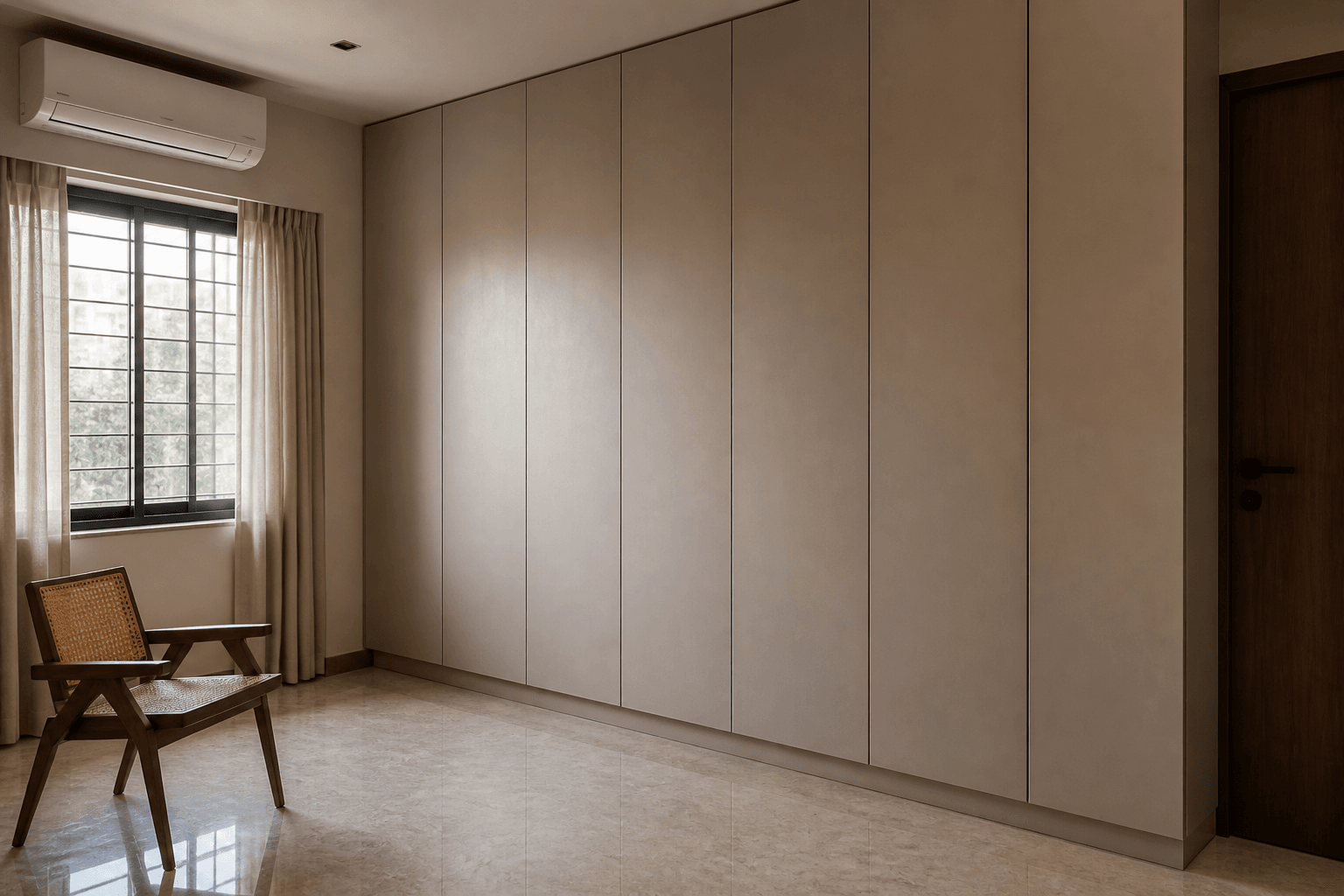 Full-height joinery along one wall of a compact room, closed doors, a clear floor and a single chair