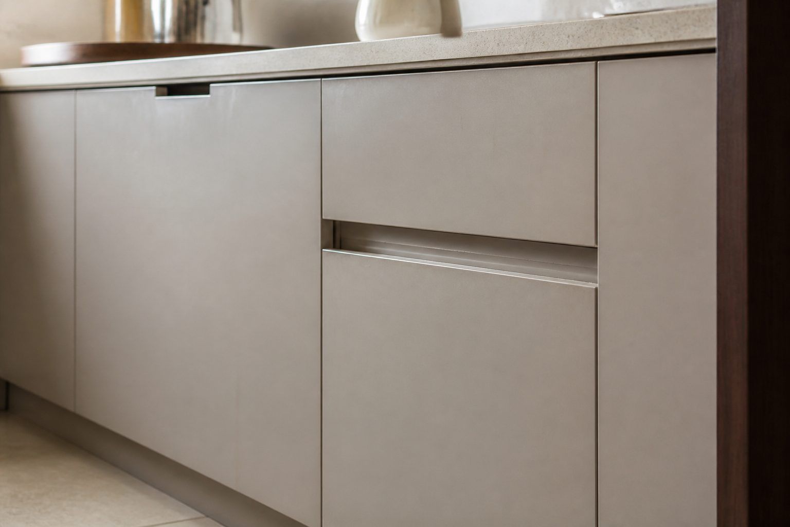 Detail of a flat kitchen shutter with a simple recessed pull and a wipeable junction in soft side light